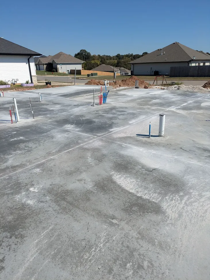 Finished concrete house slab and utility connections viewed toward the neighborhood Finished concrete house slab and utility connections viewed toward the neighborhood