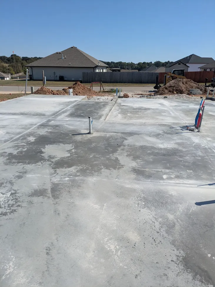 Completed concrete foundation with utility stub-outs and nearby earthmoving equipment Completed concrete foundation with utility stub-outs and nearby earthmoving equipment